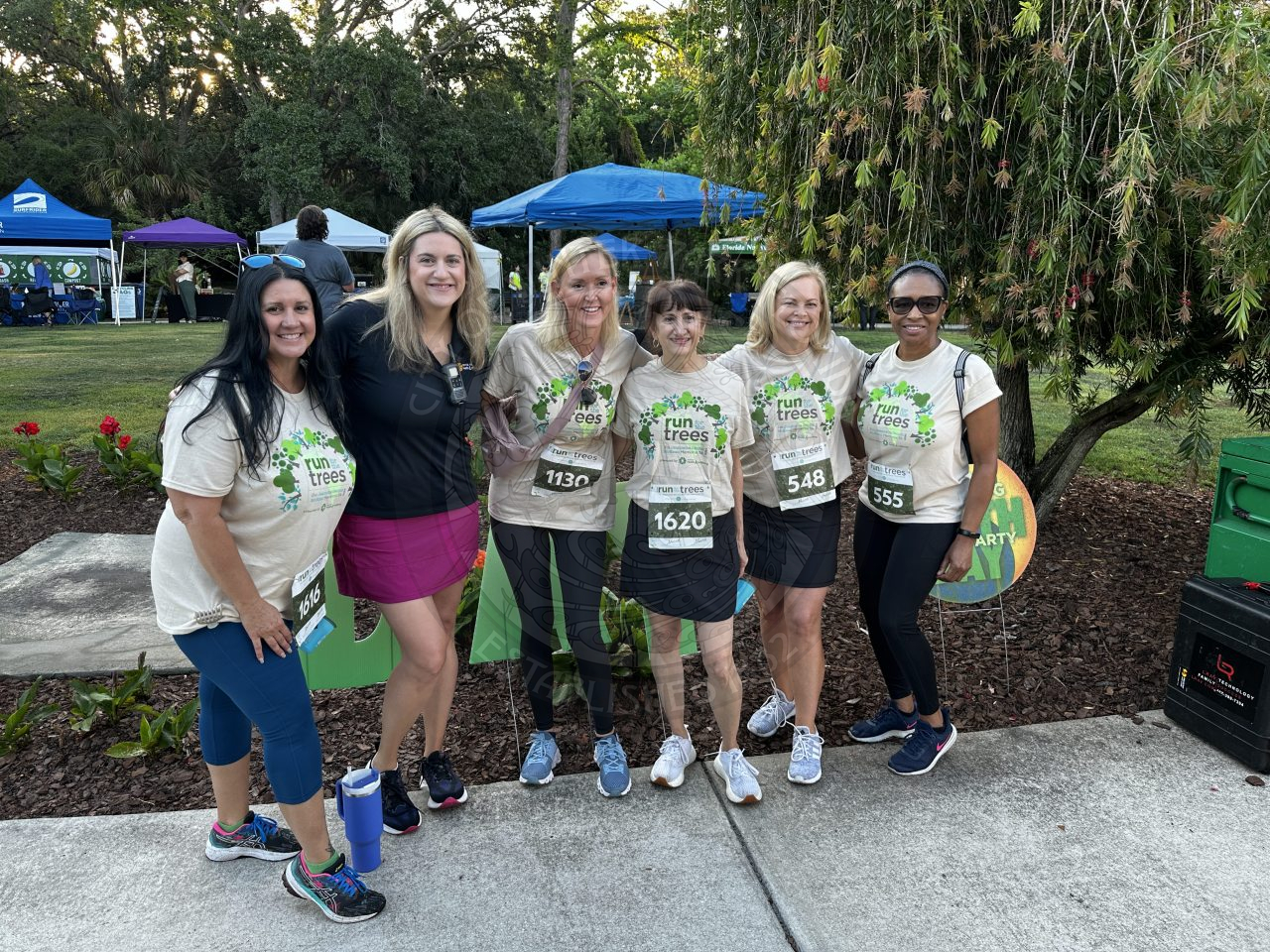 Six females standing next to each other. They are in matching shirts for the 5k they are about to walk in that say "Run for the Trees"