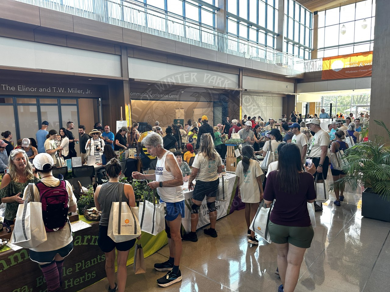 Inside the center for health and wellbeing with a bunch of pop up tents and people visiting each table to get information from the companies.