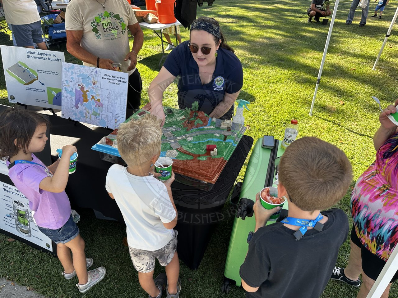 city staff member showing kids an layout of  stormwater in the city of winter park.