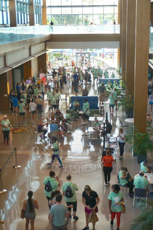 a picture taken from the second level of the building look down at alll the poeple walking around inside the Center for Health &amp; Wellbeing