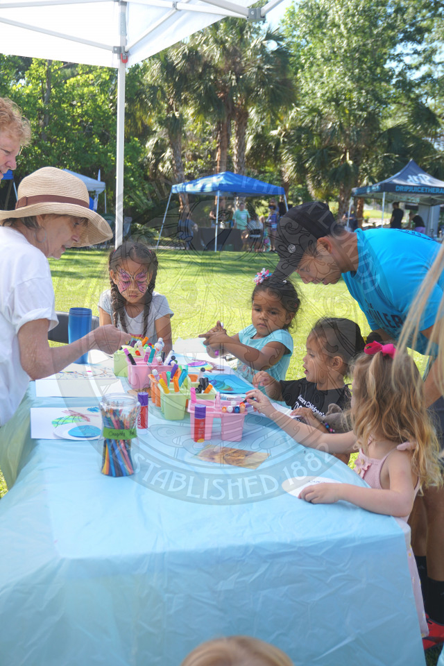 kids sitting at a table coloring with their parents right behind them watching