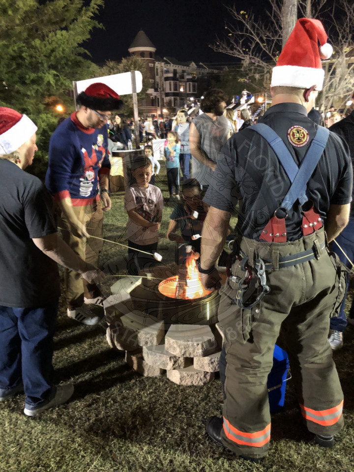 Firefighter overseeing kids and their parents roasting marshmallows for s'mores