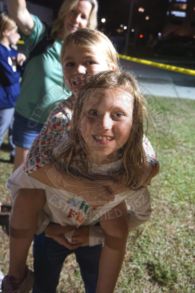 2 sisters smiling with the younger sister on the back of the older sister.