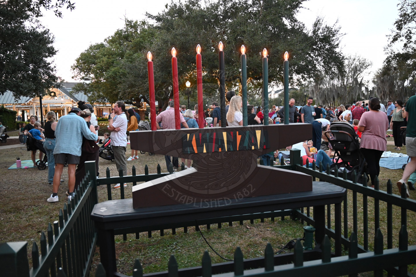kwanzaa kinora with lit candles surrounded by a gate.