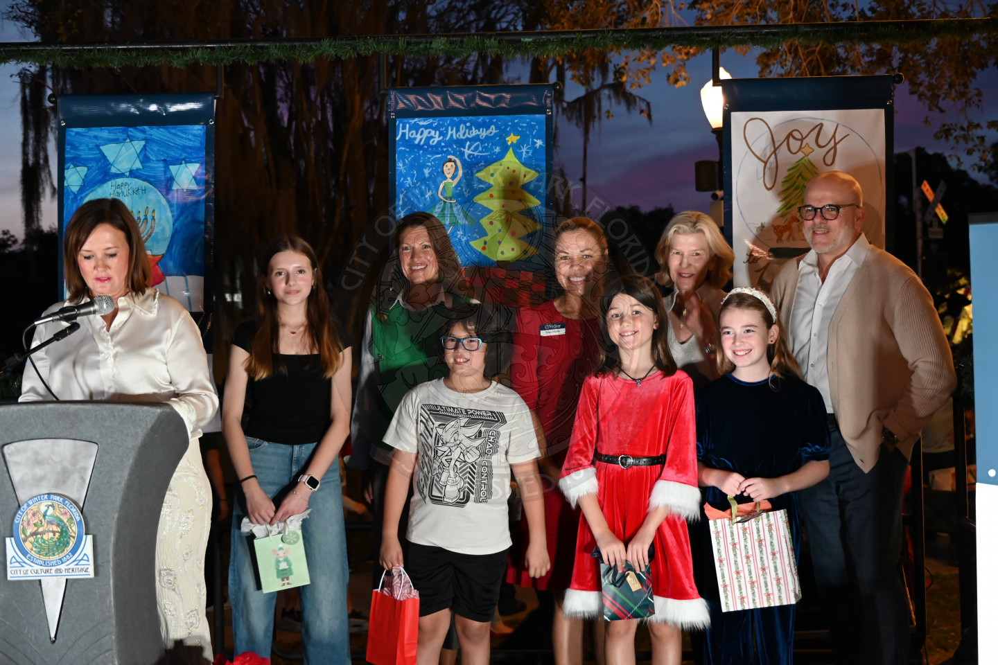 all the winners of the children's art drawing contest standing next to each other holding their gifts.