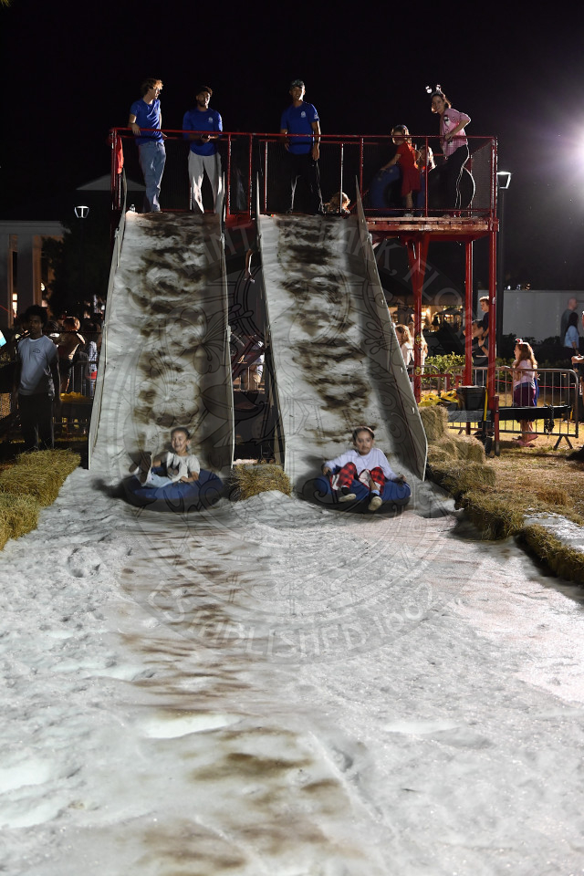 children riding inflatable tubes down to two parallel snow-covered slides.