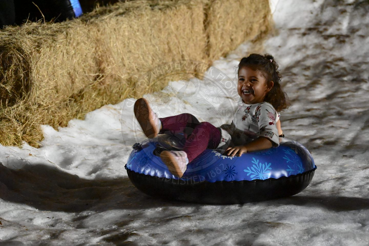 little girl sitting in a tube sliding down ice/snow hill.