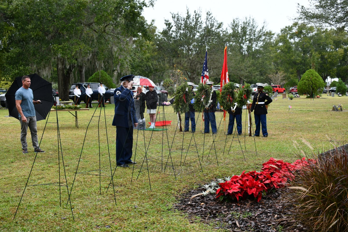 an older gentleman in uniform saluting a wreath he just placed on an easel.