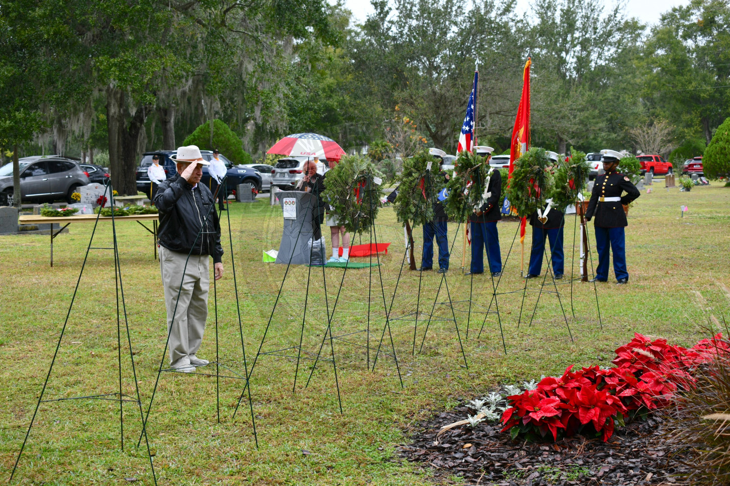 a man saluting to the wreath he just placed on an easel in row of easels.