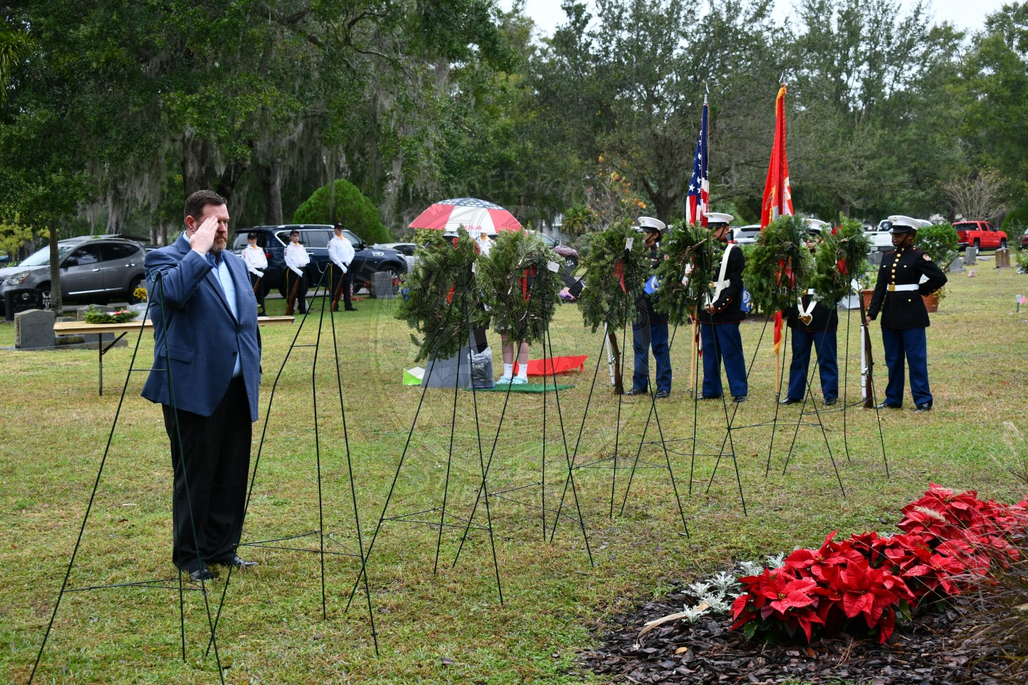 a man saluting to the wreath he just placed on an easel in row of easels.