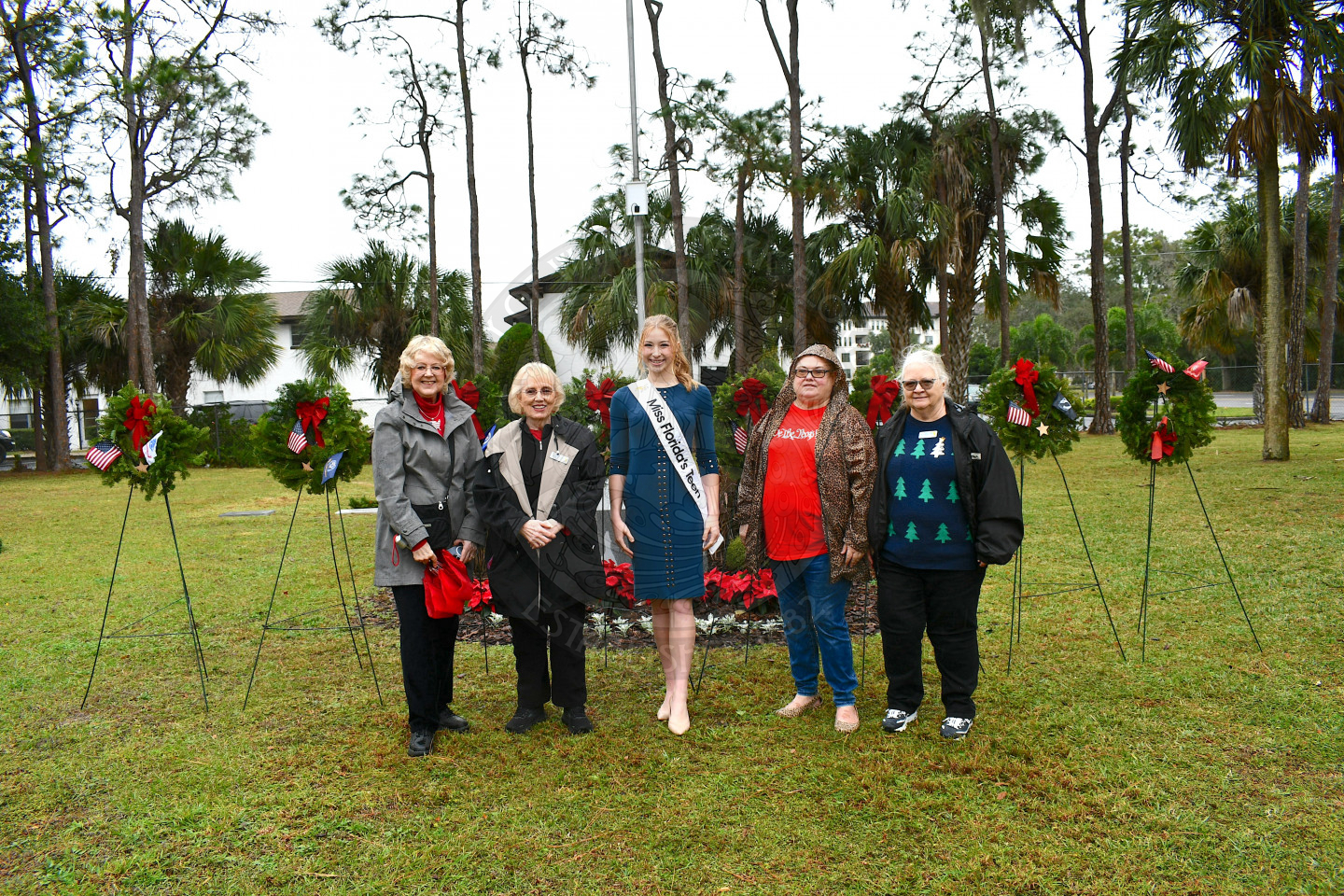 A group shot of people standing in front of the placed military wreaths.