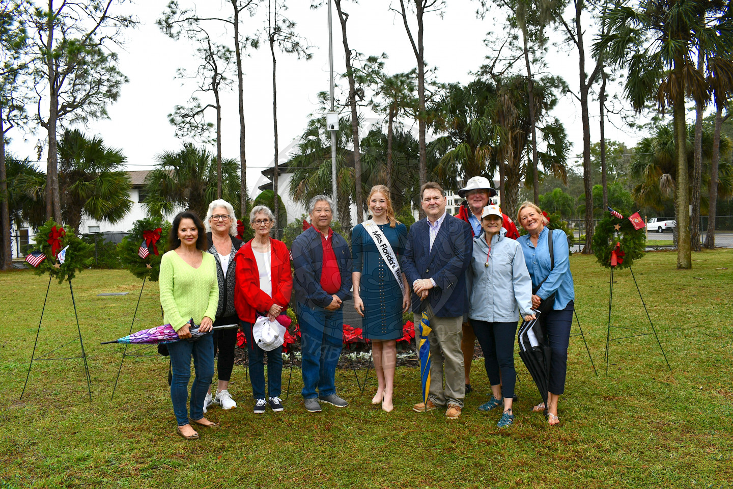 A group shot of people standing in front of the placed military wreaths.