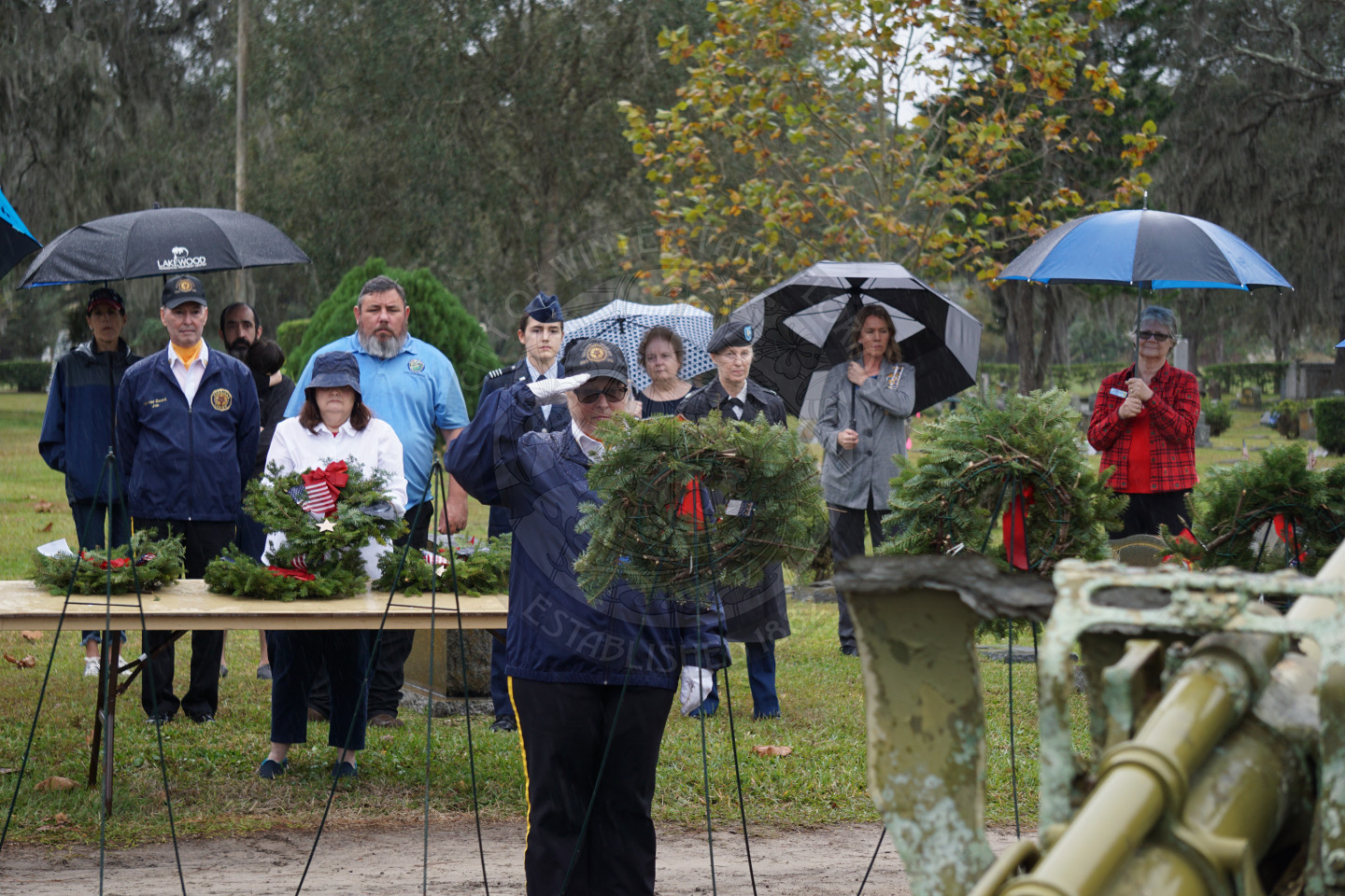 A woman in uniform saluting to the wreath placed on an easel.