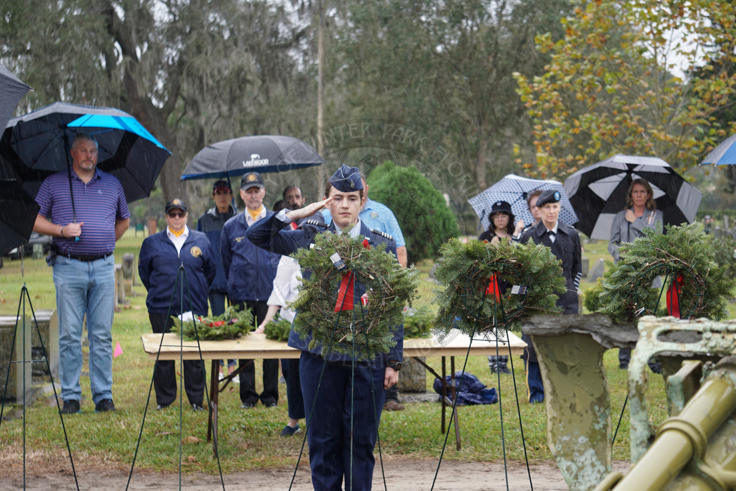 A woman in uniform saluting to the wreath placed on an easel.