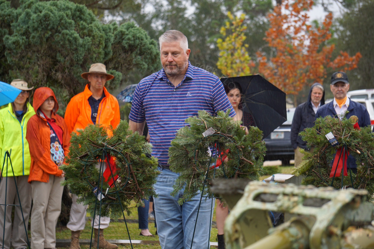 A man looking at the wreath he just places on an easle