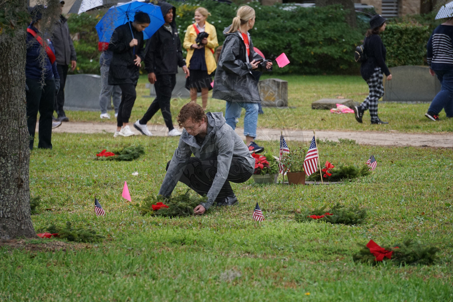 a boy bending down placing a wreath at a grave.