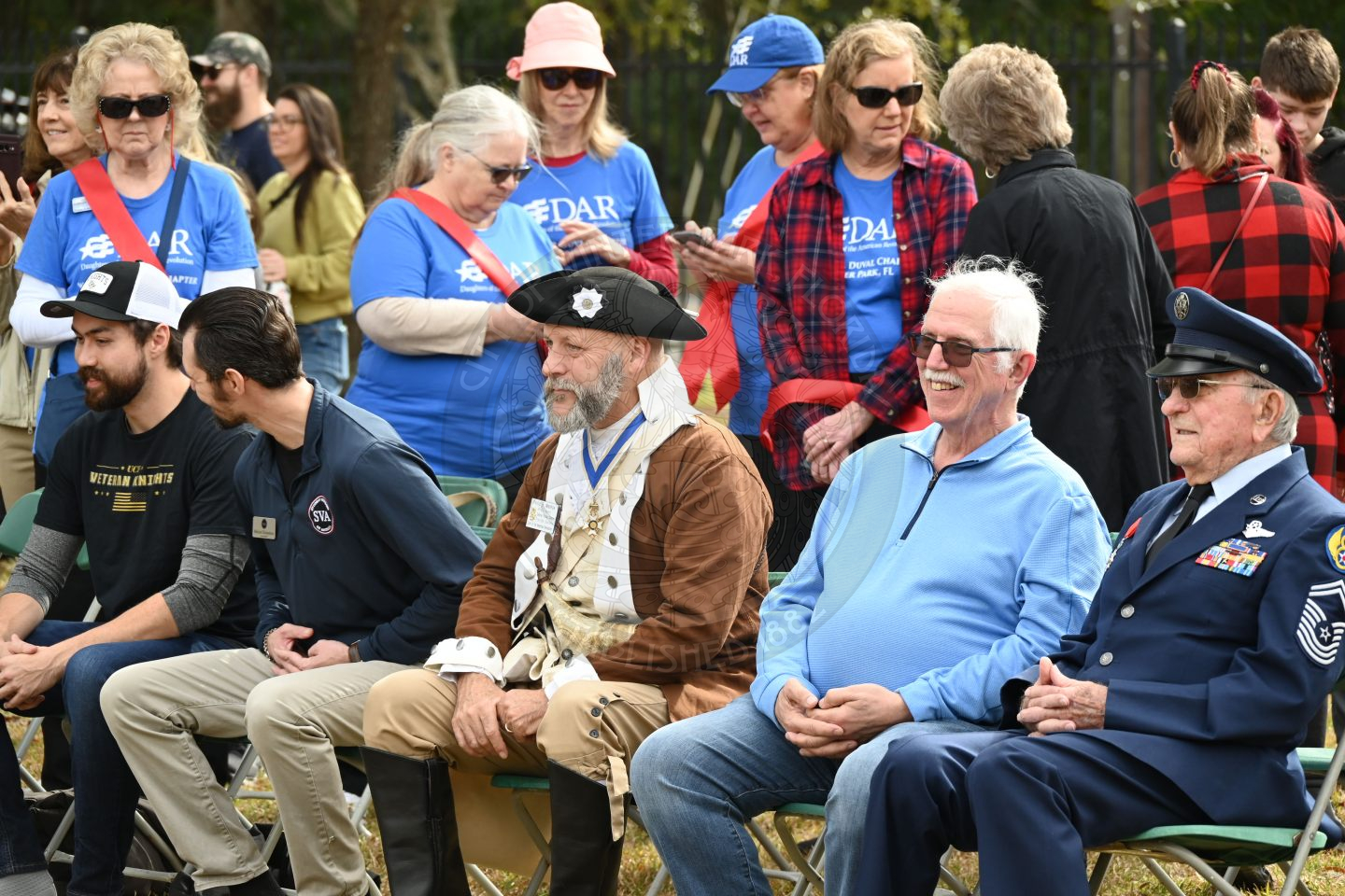 a group of olderpeople sitting in chairs with people standing behind them.