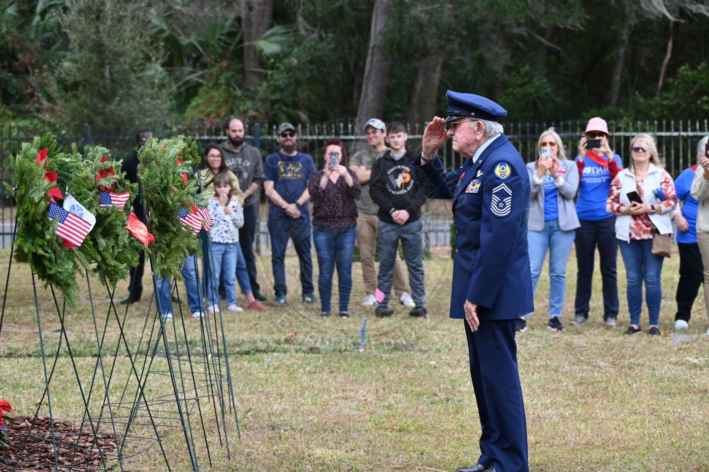 a man saluting to the miltary branch wreath he placed on a stand.