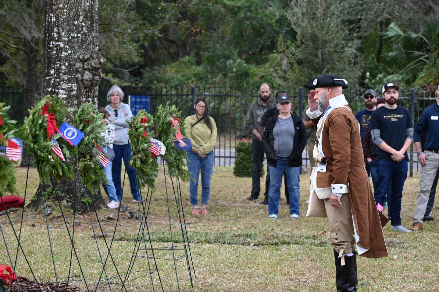 a man saluting to the miltary branch wreath he placed on a stand.