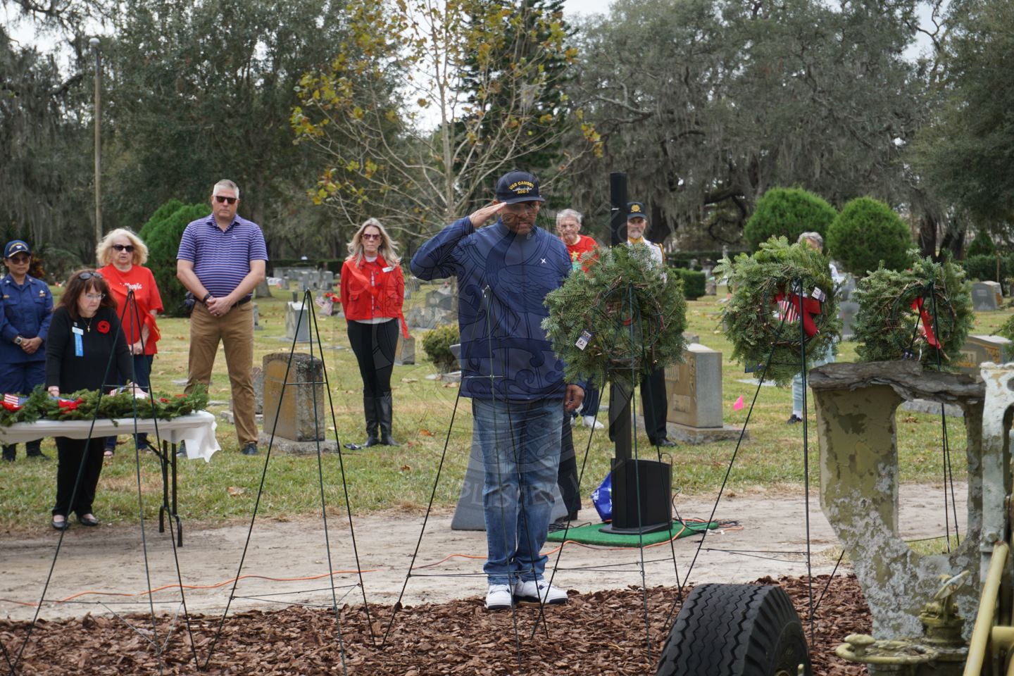 a man saluting to the miltary branch wreath he placed on a stand.