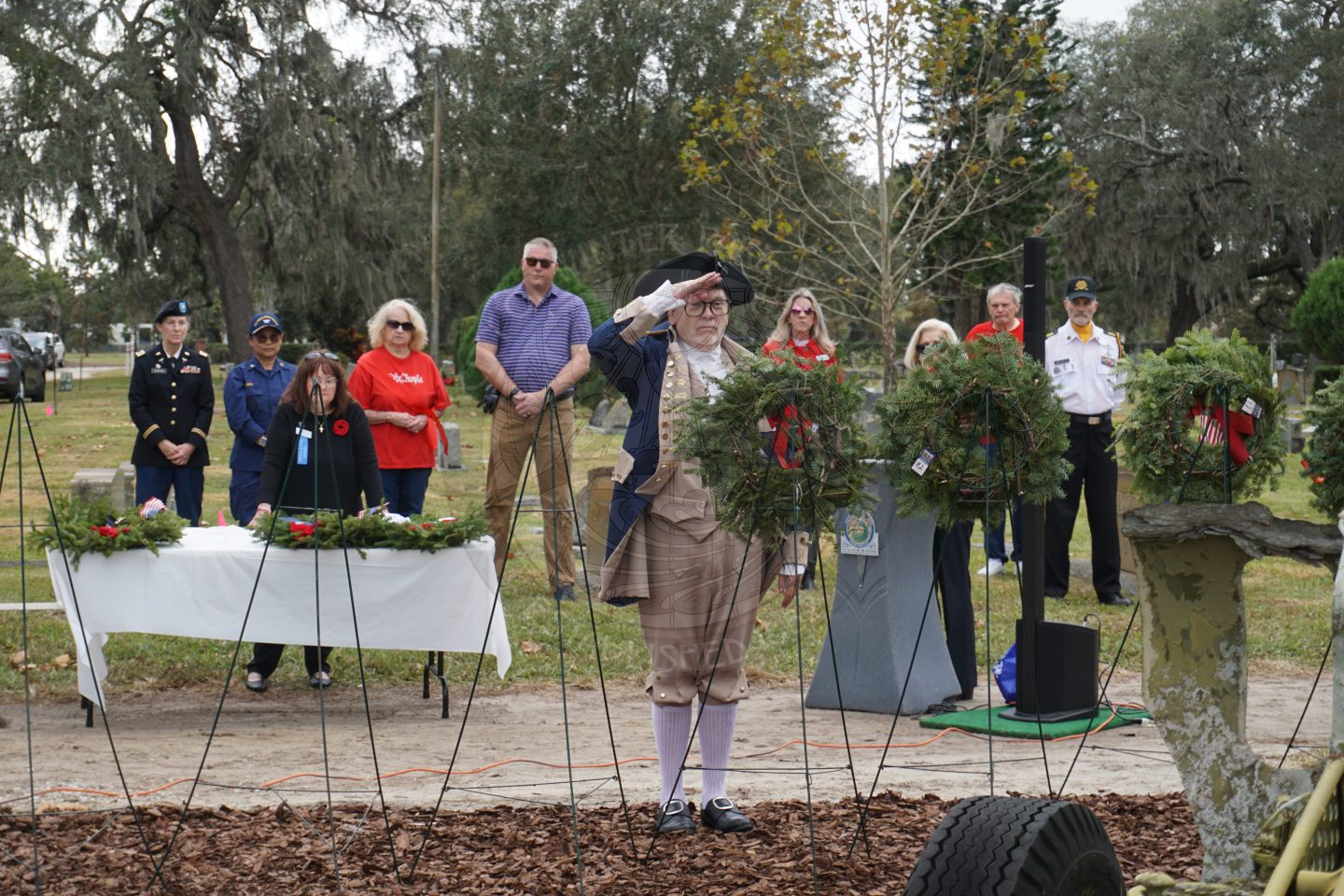 a man saluting to the miltary branch wreath he placed on a stand.