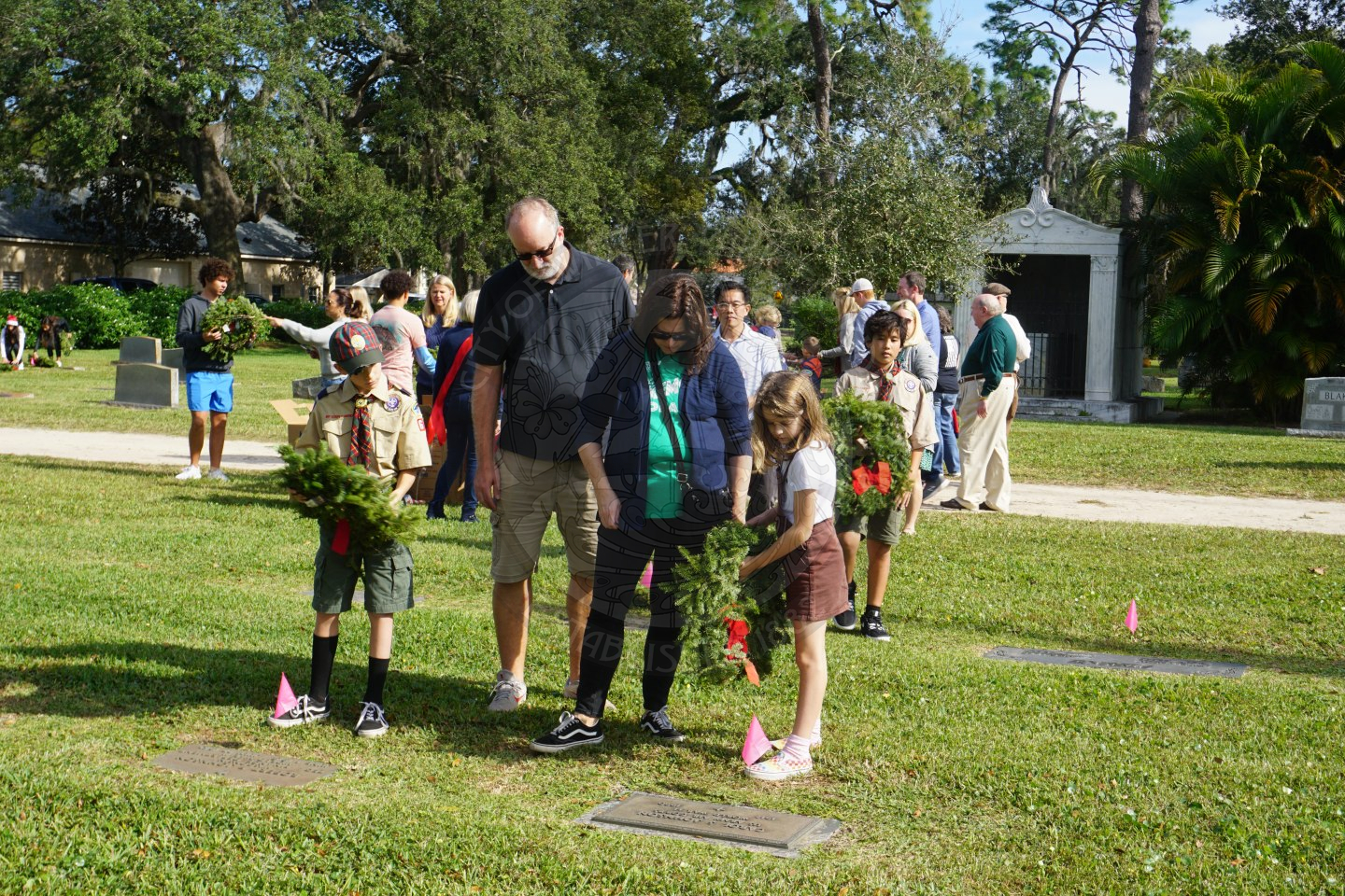 Family laying down wreaths on veterans grave