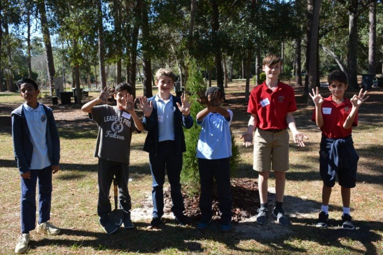 Boys posing in front of a tree showing their dirty hands in Mead Botanical Garden