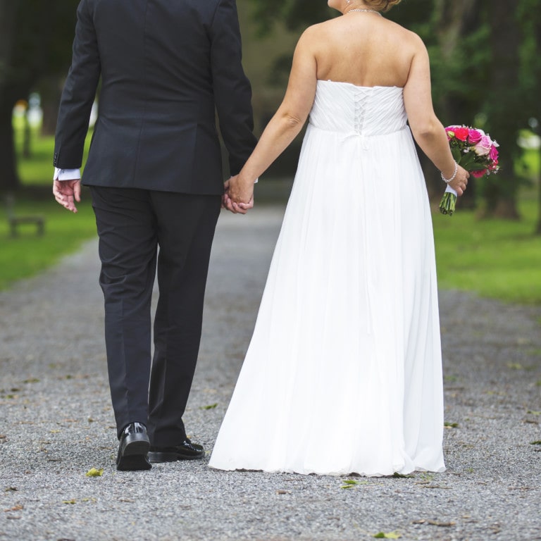 man and woman in wedding attire walking down sidewalk holding hands