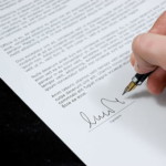 Signed document including a hand and a pen in close-up