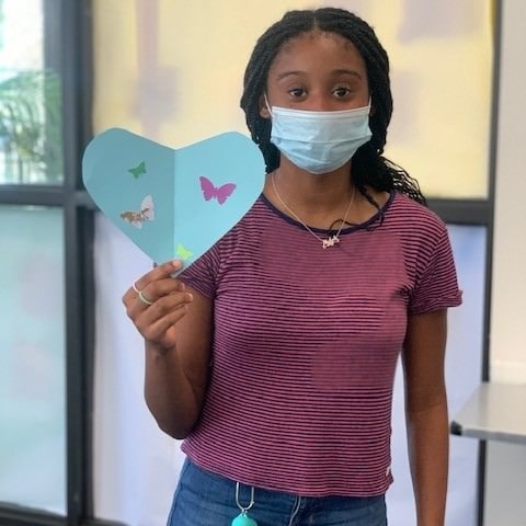 teen girl holding up her butterfly craft project