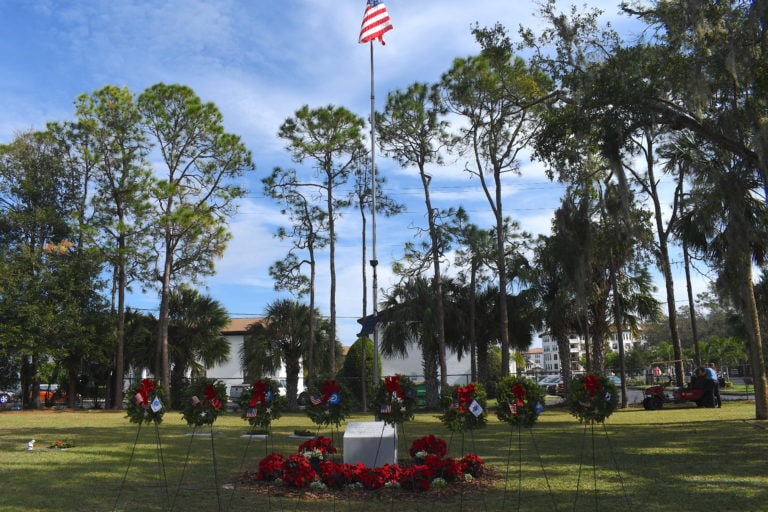 Six branch wreaths in front of American Flag
