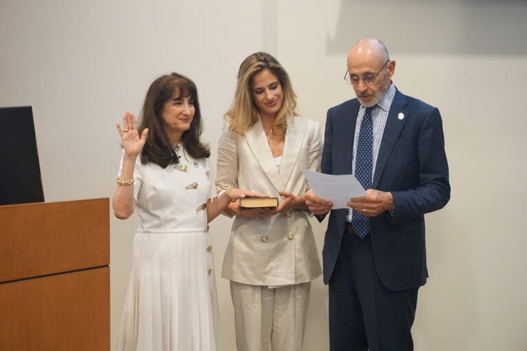 Mayor DeCiccio holding her right hand up and her left hand on a bible that her daughter is holding. Mayor's husband is standing right next to the daughter with a paper in his handing reading the oath.
