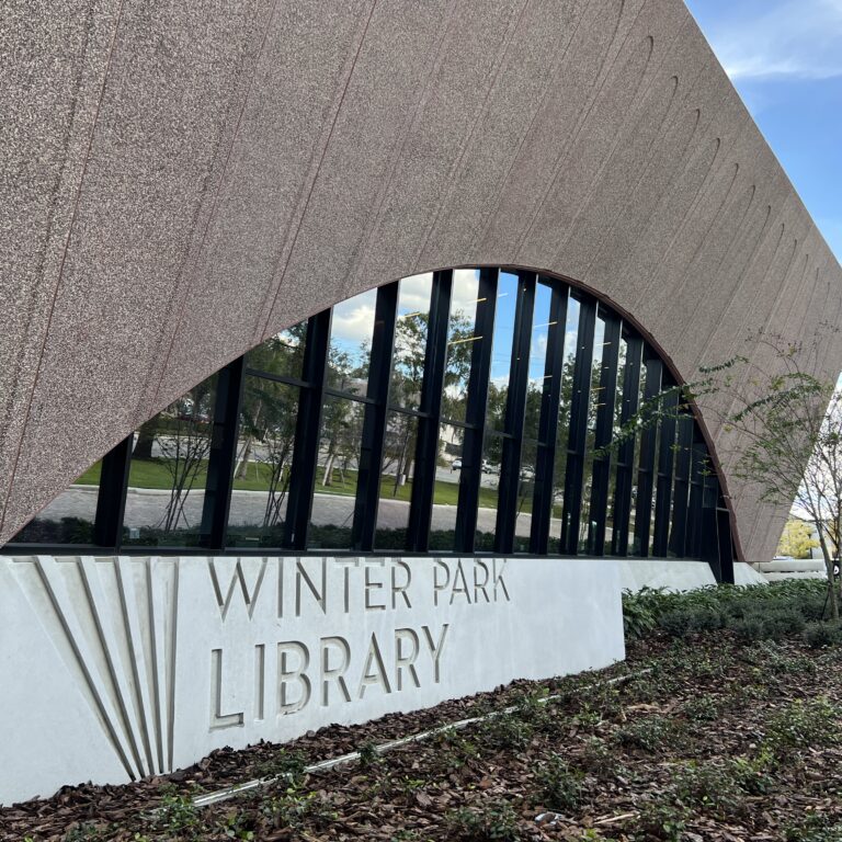 a picture of the outside building of the Winter Park Library. In front of the building is a sign that says "Winter Park Library"