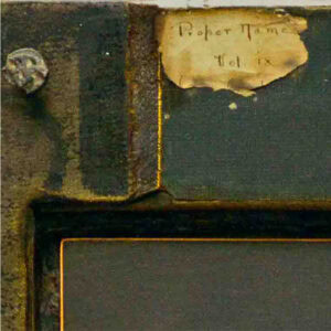 An old book encased in a transparent display. There is a yellowed piece of burnt paper stating "Proper Name" in the top left corner of the book.