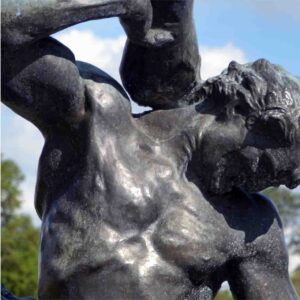 A statue depicting a muscular, nude man raising a hammer