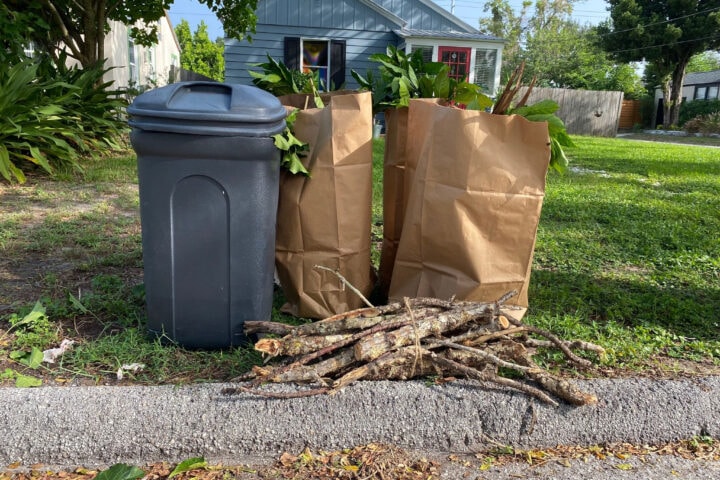 a container, bundle and bags of yard debris sitting curbside