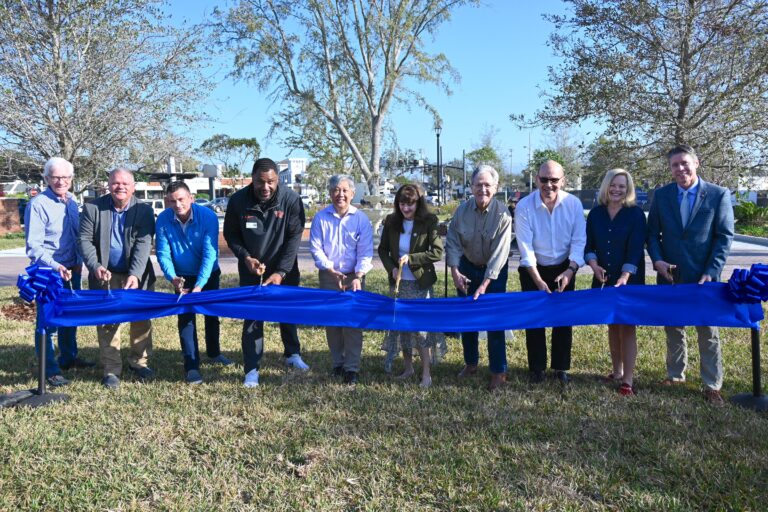 a group of people standing behind a ribbon holding scissors to cut the ribbon for the grand opening.