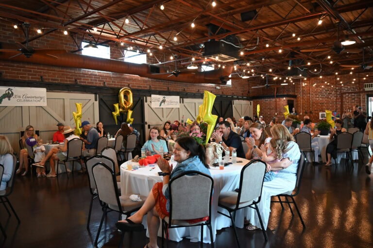 people sitting in tables clapping at someone who is presenting.