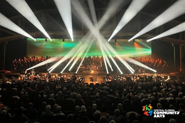 a stage full of performers with lights shining to the crowd of the audience