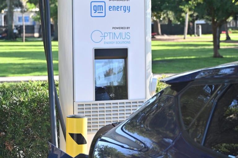 a bunch of people standing in front of ev charging stations