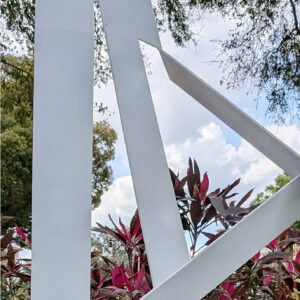 The sculpture resembles the letter "A" with abstract shapes with intersecting forms, painted in white.