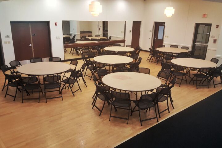 Cypress Room event set-up example with round tables and black chairs, ideal for meetings or gatherings.