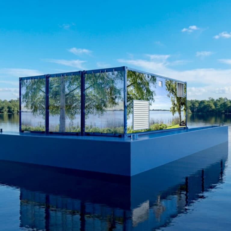 A large mirror on a pilot project platform reflects trees and water, blending with the lakeside scenery under a clear sky.
