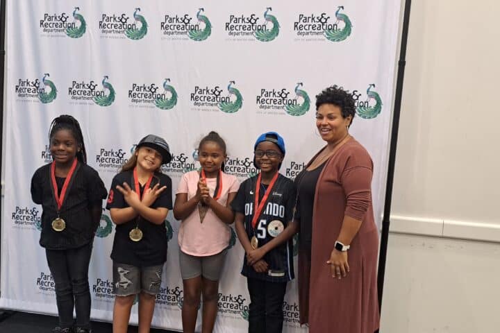 Kids proudly displaying their medals at a Winter Park Parks & Recreation award ceremony, showcasing community engagement and youth success.