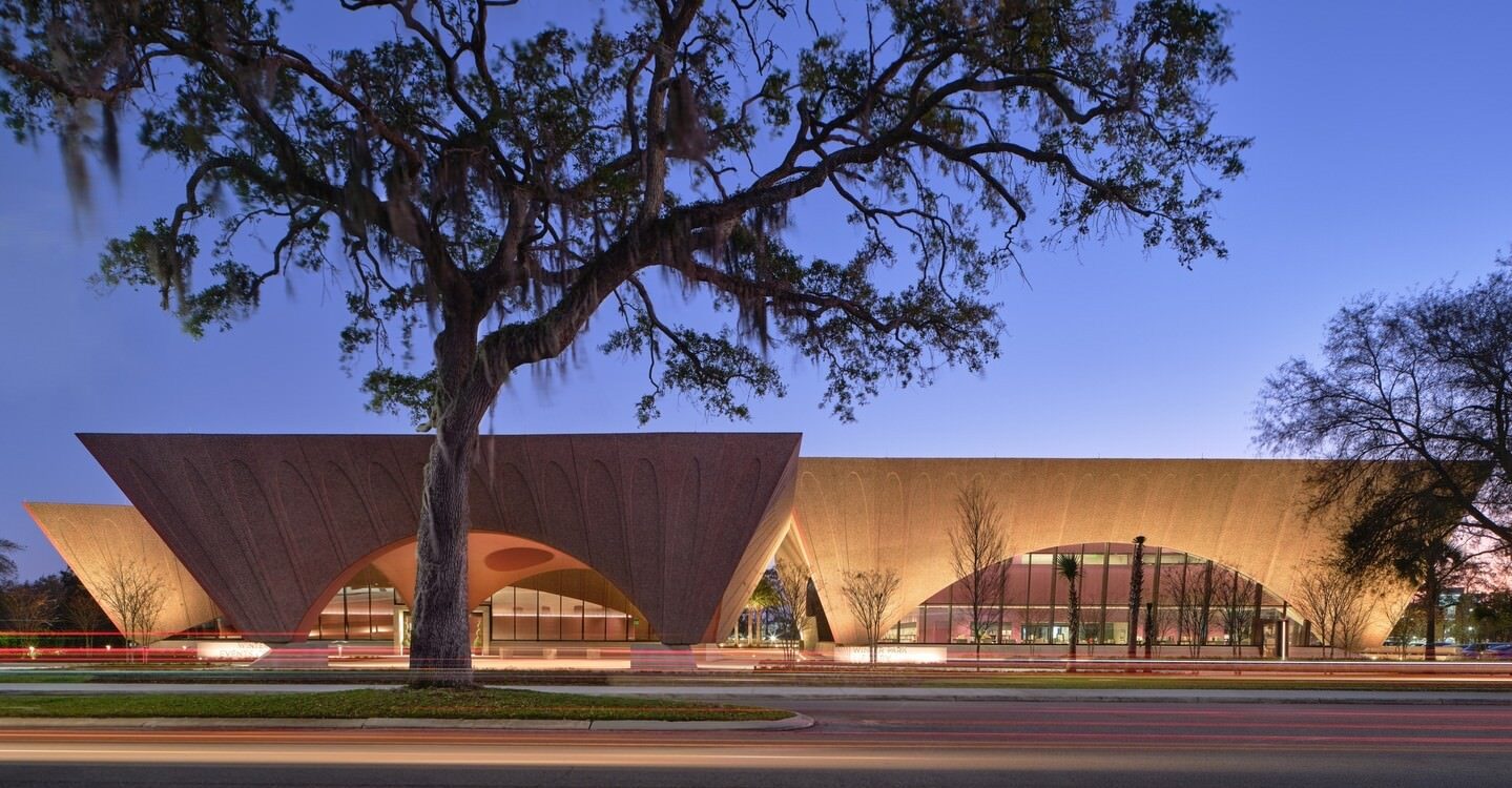 Modern architectural building in Winter Park, Florida, illuminated at dusk with a large tree in the foreground, showcasing city development, scenic beauty, and vibrant downtown lifestyle.